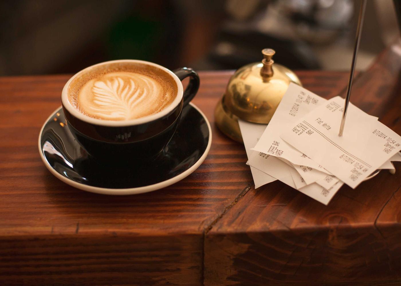 A table card with a QR code standing on a café counter, next to a flat white